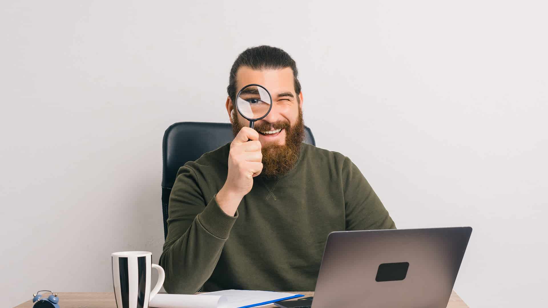 man-at-desk-with-magnifying-glass-search